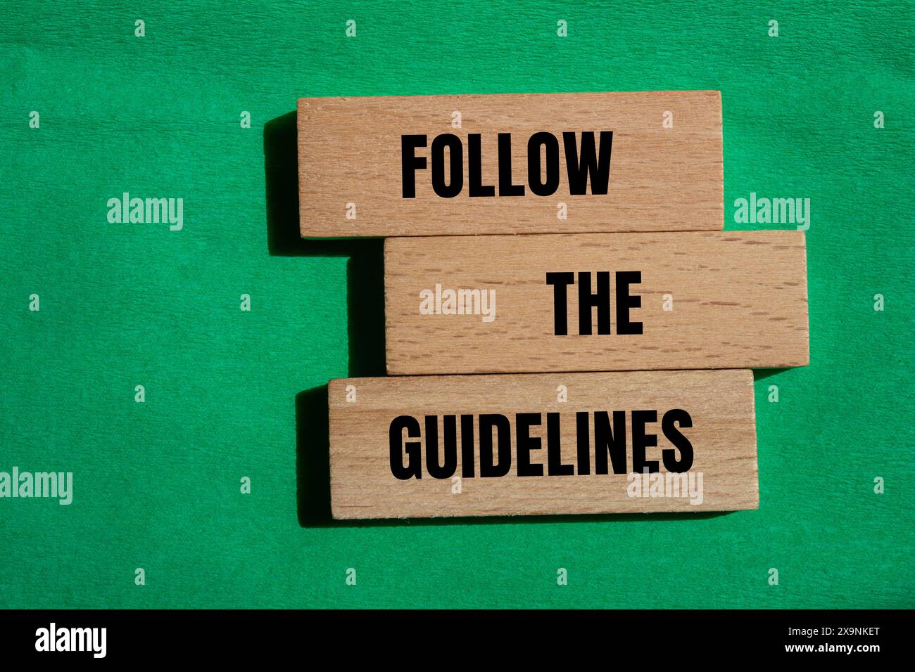 Folgen Sie den Hinweisen auf Holzblöcken mit grünem Hintergrund. Konzeptionell Befolgen Sie das Richtliniensymbol. Kopierbereich. Stockfoto