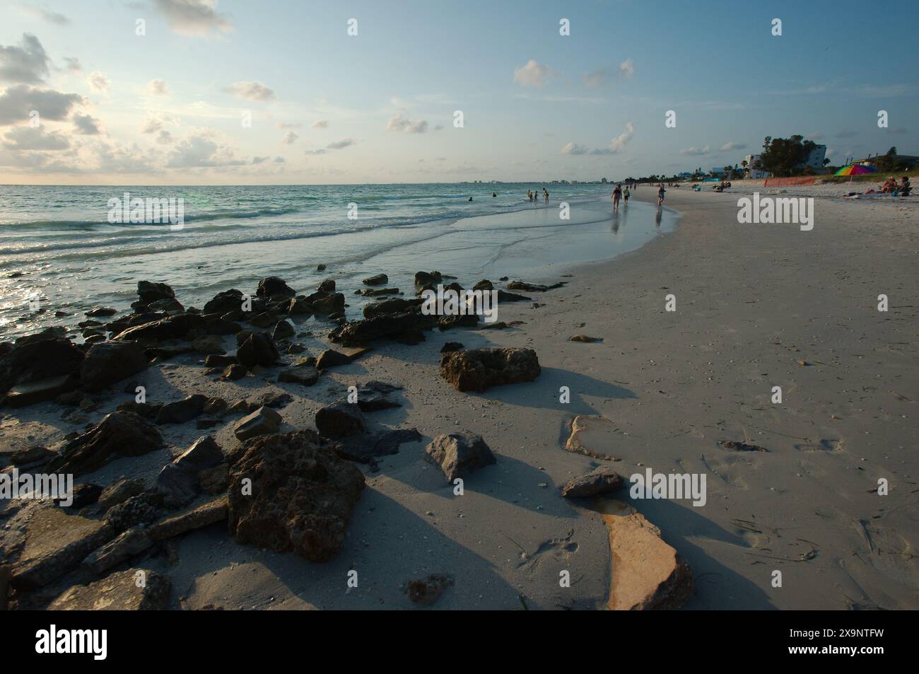 Weitwinkelblick auf den Pass-a-Grille Strand in St. Pete Beach Florida mit Blick nach Norden. Felsen und mehrere Leute, die im Sand und im Wasser spazieren, nahe am Set Stockfoto