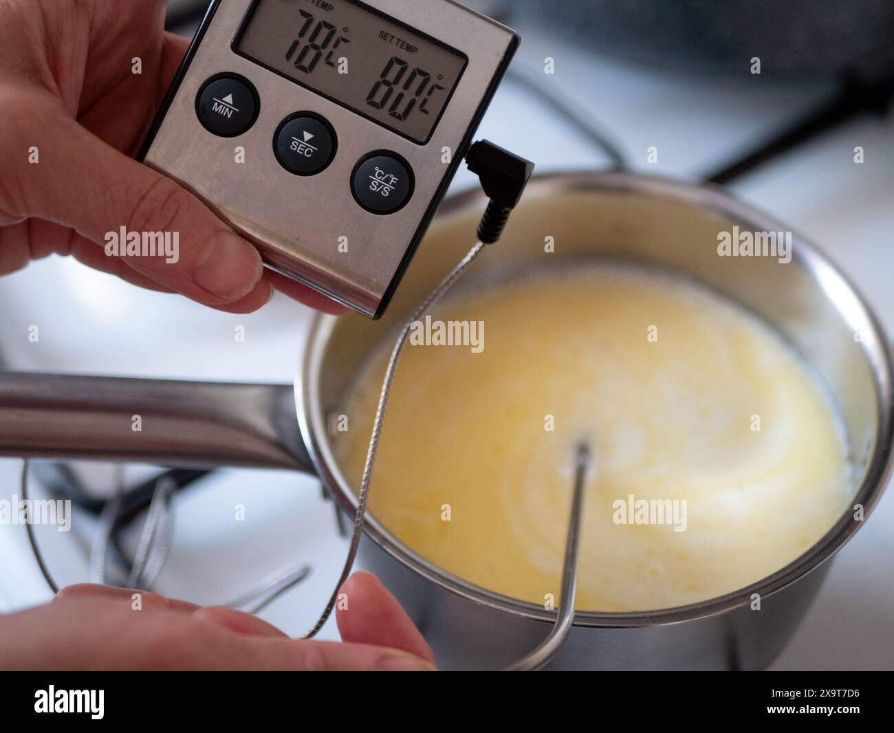 Verwendung eines digitalen Lebensmittelthermometers beim Kochen, selektiver Fokus. Die Temperatur einer Flüssigkeit wird auf einer Digitalanzeige angezeigt Stockfoto