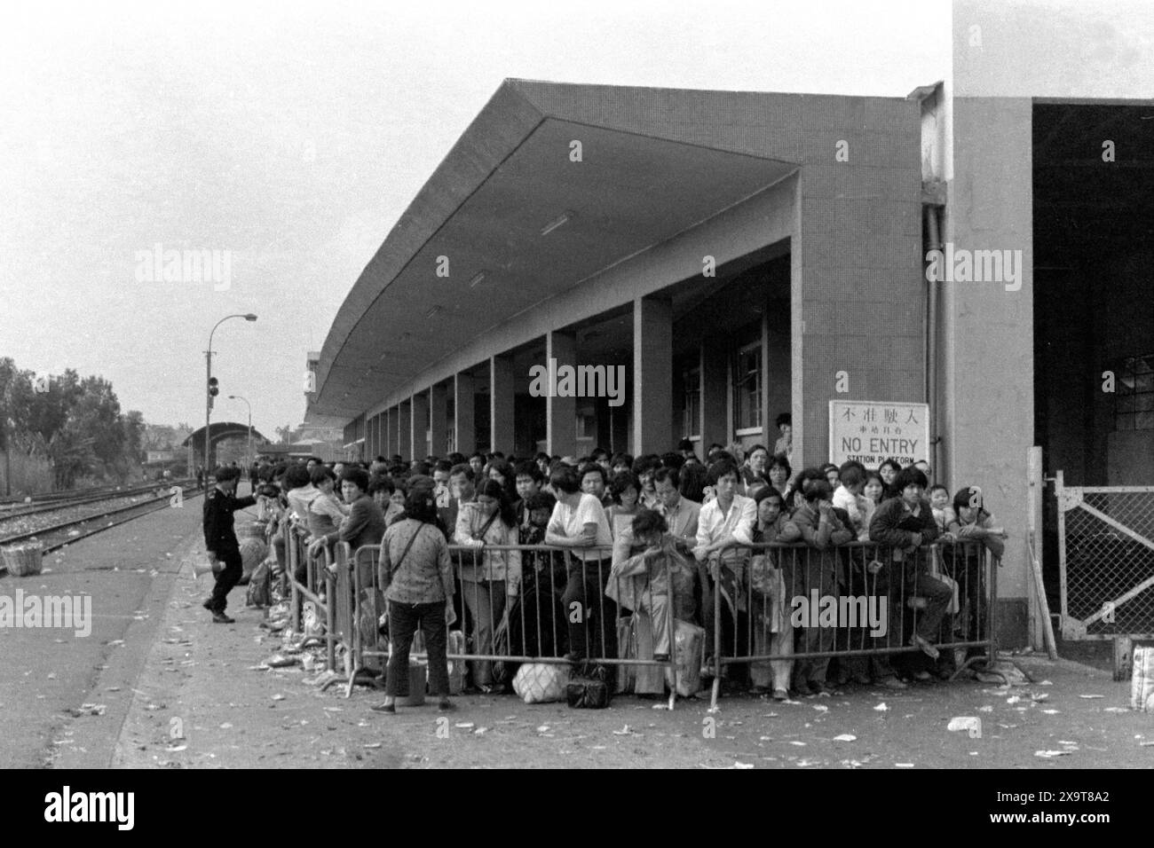 Passagiere, die auf einen Dieselzug in Richtung Süden warten, Lo Wu Bahnhof, Kowloon-Canton Railway, Hongkong, Lunar New Year 1981. Die wartenden Leute sind alle gerade vom chinesischen Festland nach Hongkong zurückgekehrt. Die Polizisten auf dem Bahnsteig sind aufgrund der hohen Passagierzahlen in der Weihnachtszeit mit dem Crowdmanagement beschäftigt. Dies geschah, bevor die KCR Anfang der 1980er Jahre elektrifiziert wurde und die Bahnhöfe und Anlagen modernisiert wurden. Stockfoto