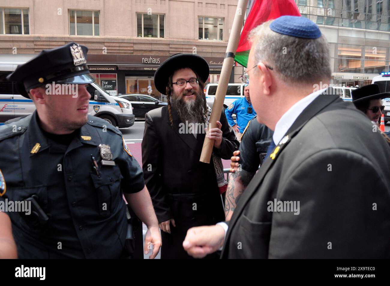 Ein Mitglied von Neturei Karta, Zentrum, die ultra-orthodoxe, antizionistische Juden sind, protestiert auf der Straße in der Nähe eines israelischen Unterstützers, rechts, während der 59. Jährlichen Israel Day Parade. Die Israel Day Parade zum Gedenken an die jüdische Kultur zieht Nachtschwärmer, Wagen und israelisch-amerikanische Organisationen nach Midtown Manhattan, New York City. Die Parade fand fast acht Monate nach Beginn des israelisch-Hamas-Krieges statt. Die diesjährige Parade konzentrierte sich auf die israelische Solidarität im andauernden Krieg. Das New York City Police Department erhöhte die Sicherheit für die Parade aufgrund von Befürchtungen der propalästinensischen Proteste. Stockfoto