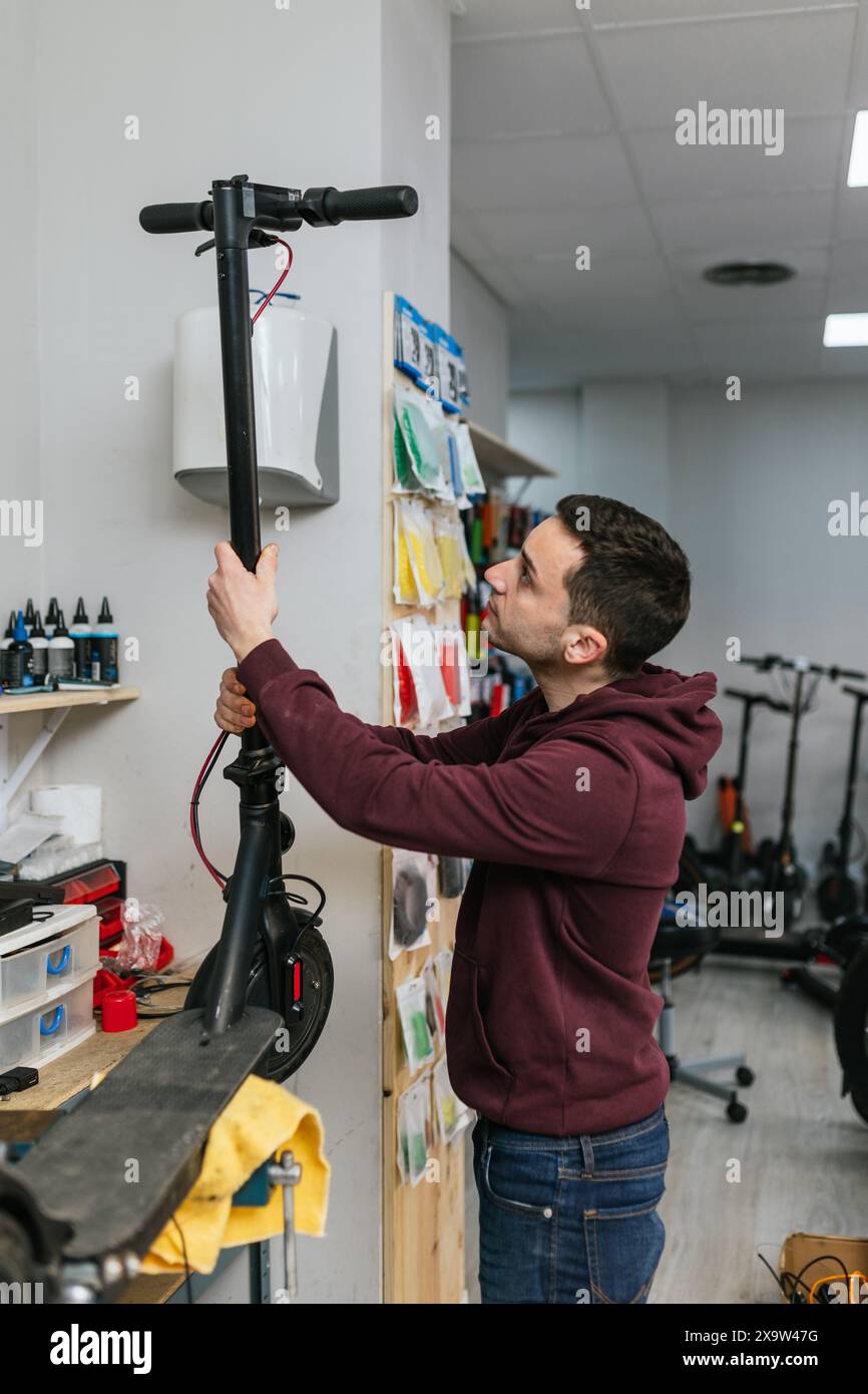 Der Mechaniker überprüft mit einem ernsthaften Ausdruck einen Elektroroller, den er gerade repariert hat Stockfoto
