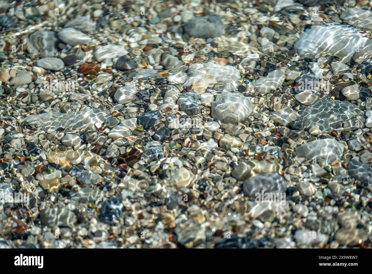 Strand mit bunten kleinen runden Steinen an einem sonnigen Tag Stockfoto