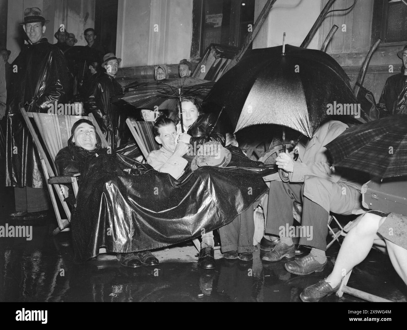 Aktuell 14-1946: Der Kampf um Urlaub. Die Leute sitzen in Liegestühlen mit Sonnenschirmen im Regen, um Tickets für den Urlaub zu bekommen. Foto: Thorbjørn Skotaam / aktuell / NTB ***Foto ist nicht bildverarbeitet*** Stockfoto