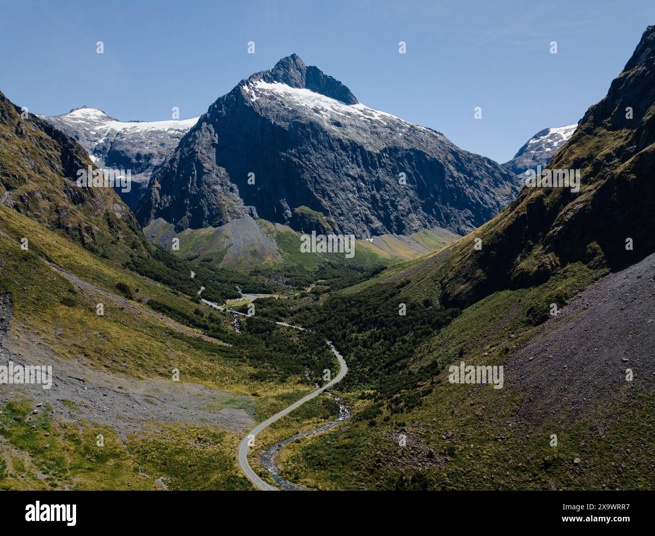 Hoch aufragende Berggipfel mit Schnee und üppig grünen Tälern Stockfoto