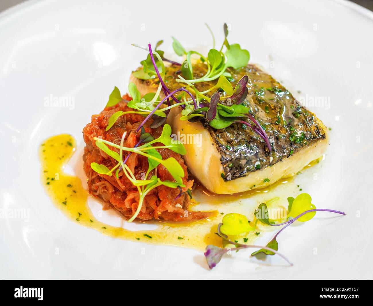 Seehecht im Biskayanischen Stil, garniert mit Brunnenkresse-Sprossen. Baskische Landküche. Stockfoto