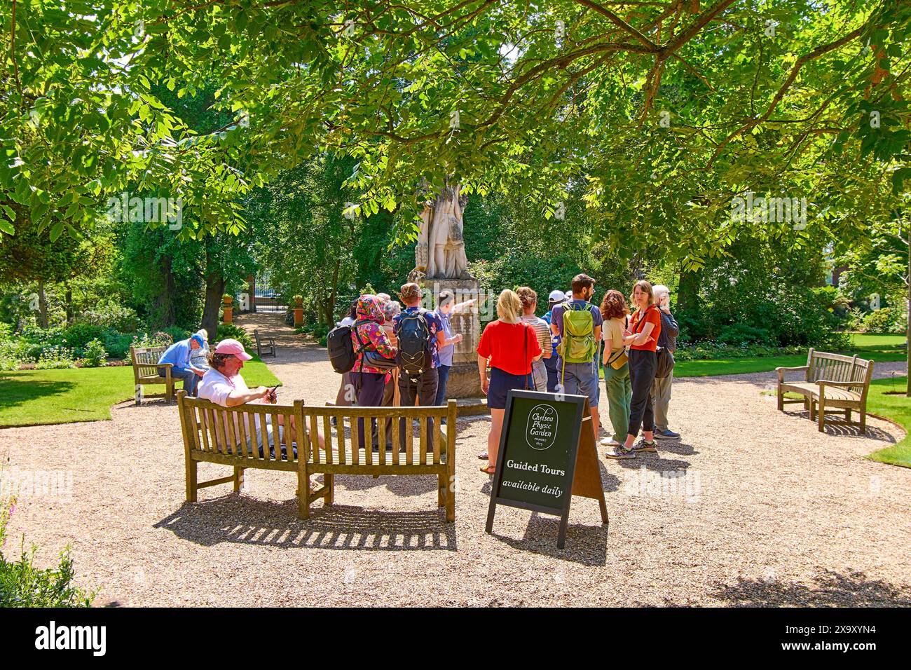 Chelsea Physic Garden Gruppe von Touristen, die auf eine Führung neben der Statue von Hans Sloane warten Stockfoto