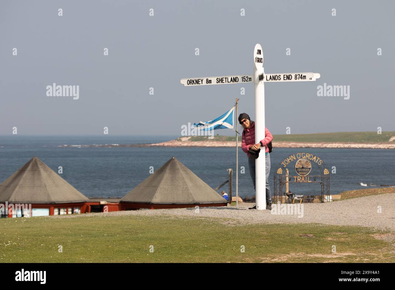 Ein Besucher posiert mit einem Schild in John O'Groats, Schottland, nahe dem nördlichsten Punkt des schottischen Festlandes Stockfoto