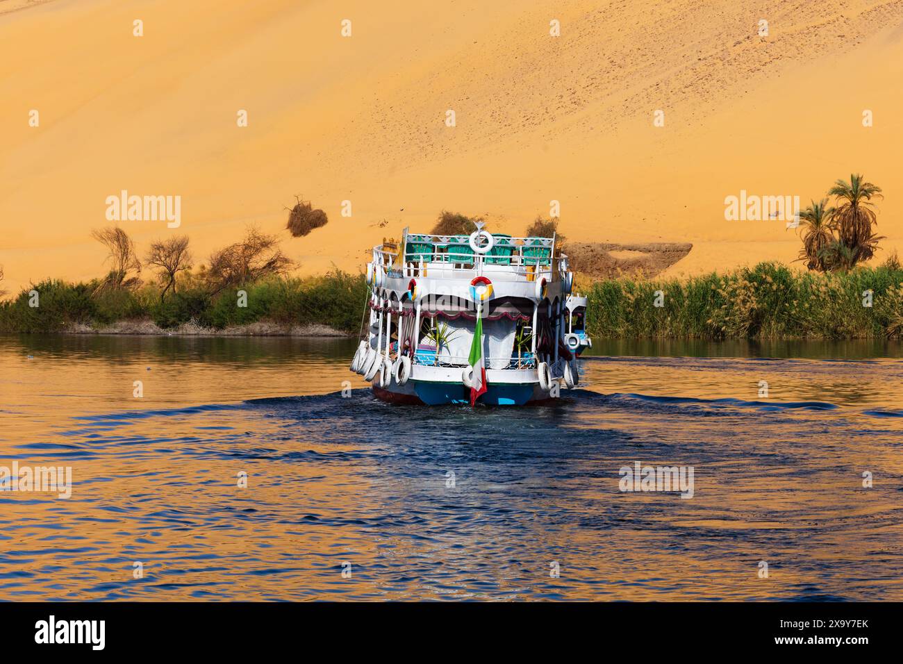 Touristische Tour Kreuzfahrt Boot auf dem Nil mit Reflexionen von der Sahara Wüste an den Ufern. Assuan. Ägypten Stockfoto