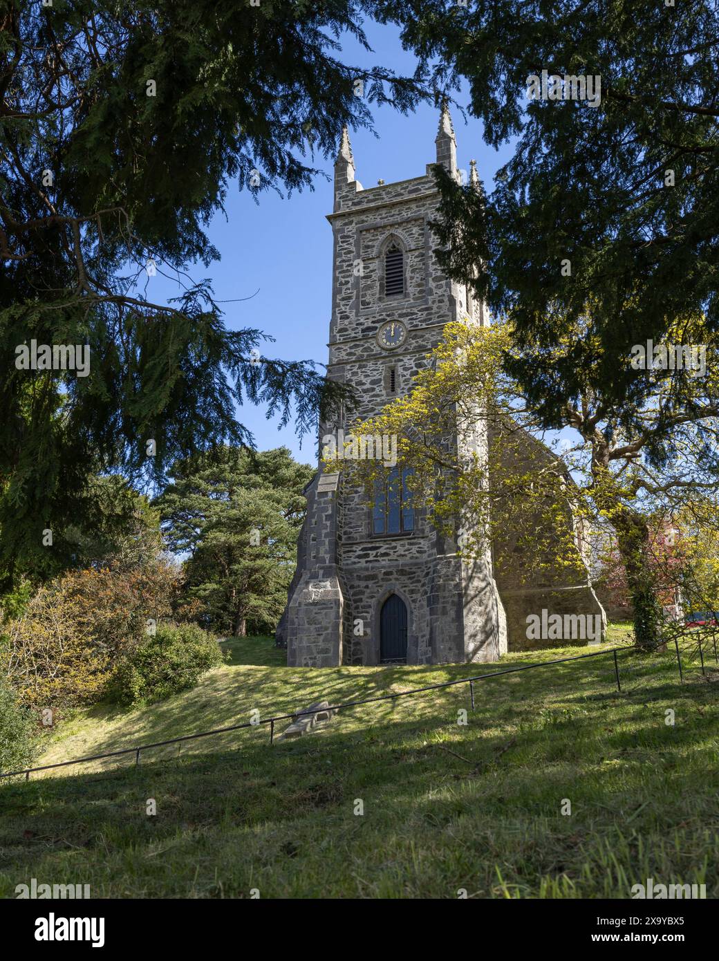 St. Mary's Church, Mona Road, Menai Bridge, Anglesey, Wales. An einem sonnigen Tag durch Bäume von der Straße aus gesehen. Stockfoto