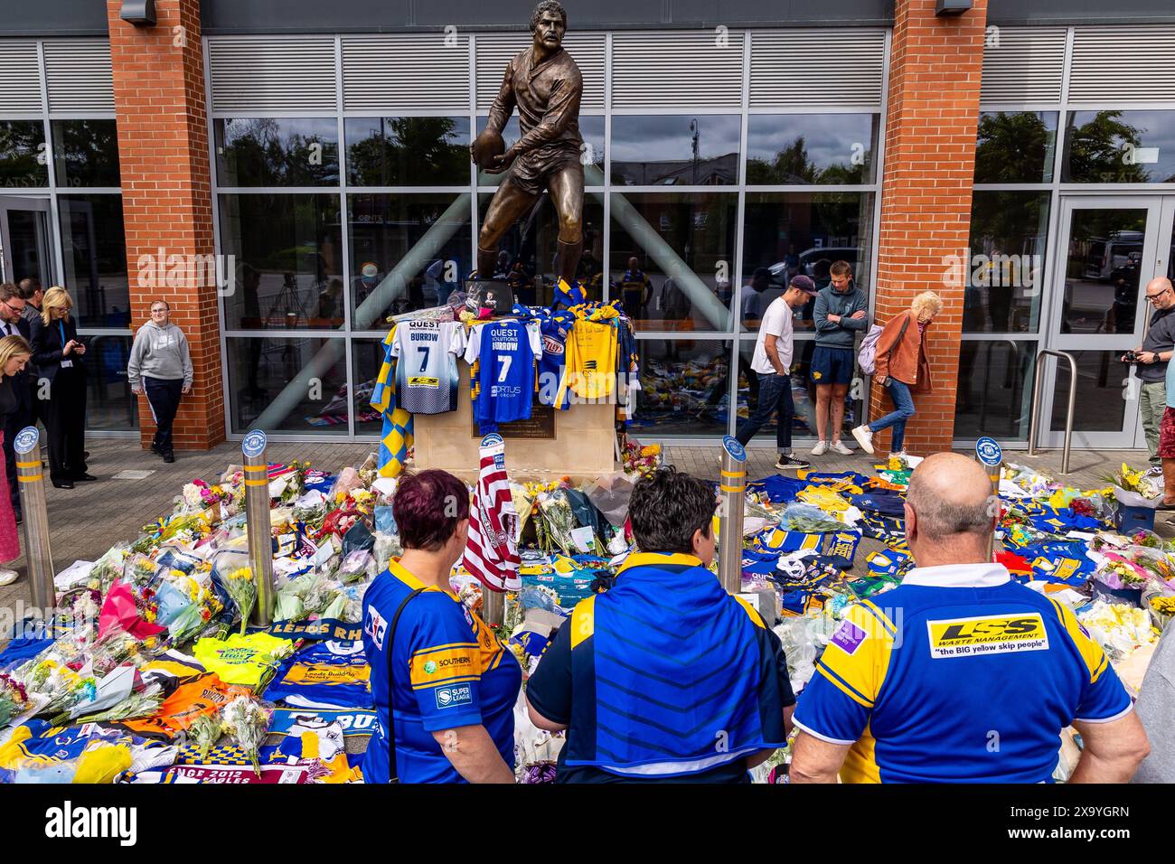 Leeds, Großbritannien. Juni 2024. Tribut an Rob Burrow im Headingley Stadium nach seinem Tod. Drei Fans, die Leeds Rhinos Shirts tragen, bewundern die Tribut kurz nachdem sie Rugbyshirts am Tatort platziert hatten. Quelle: Neil Terry/Alamy Live News Stockfoto