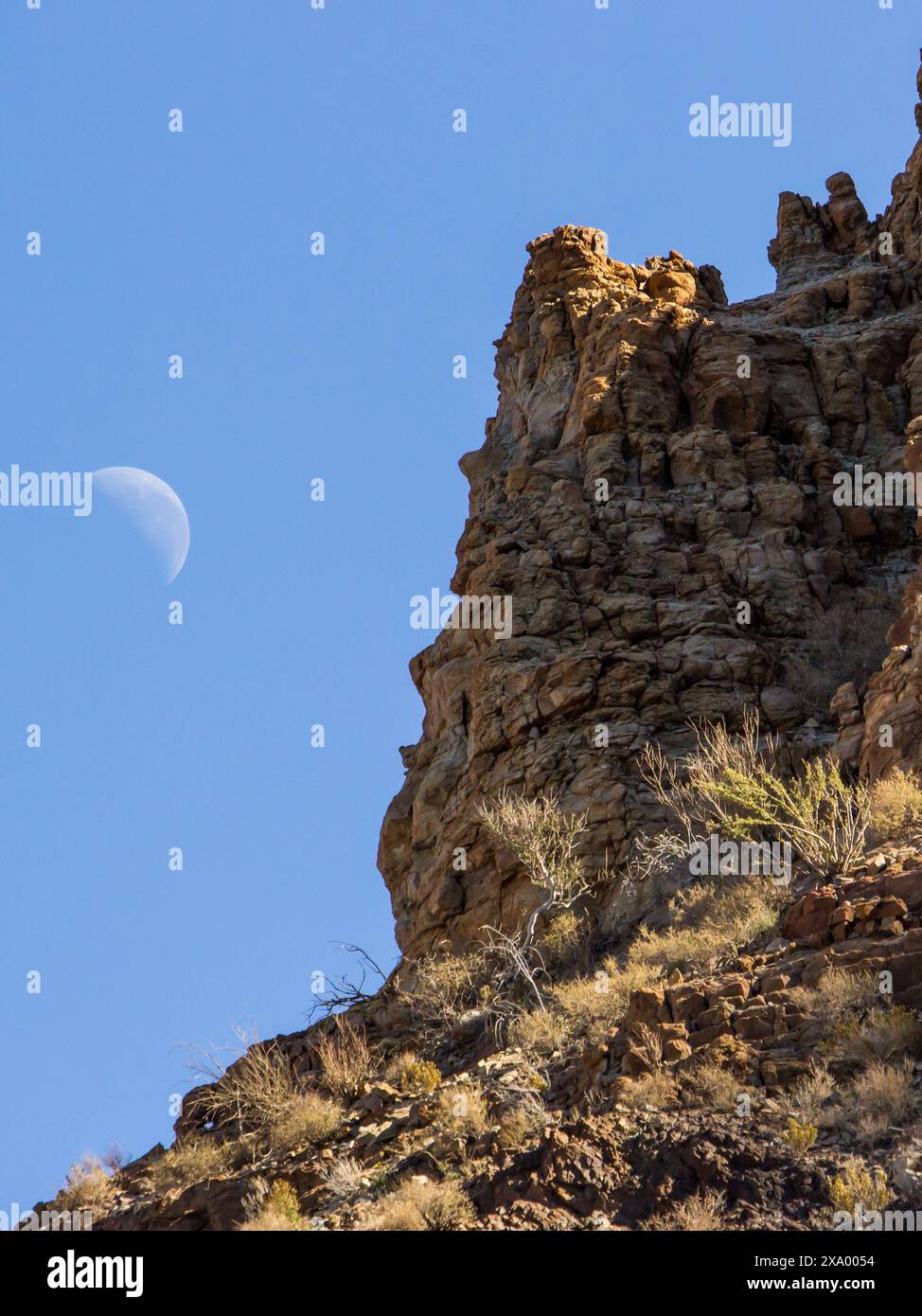 Eine zerklüftete Klippe im Fish River Canyon von Namibia mit dem wachsenden Mond im Hintergrund Stockfoto