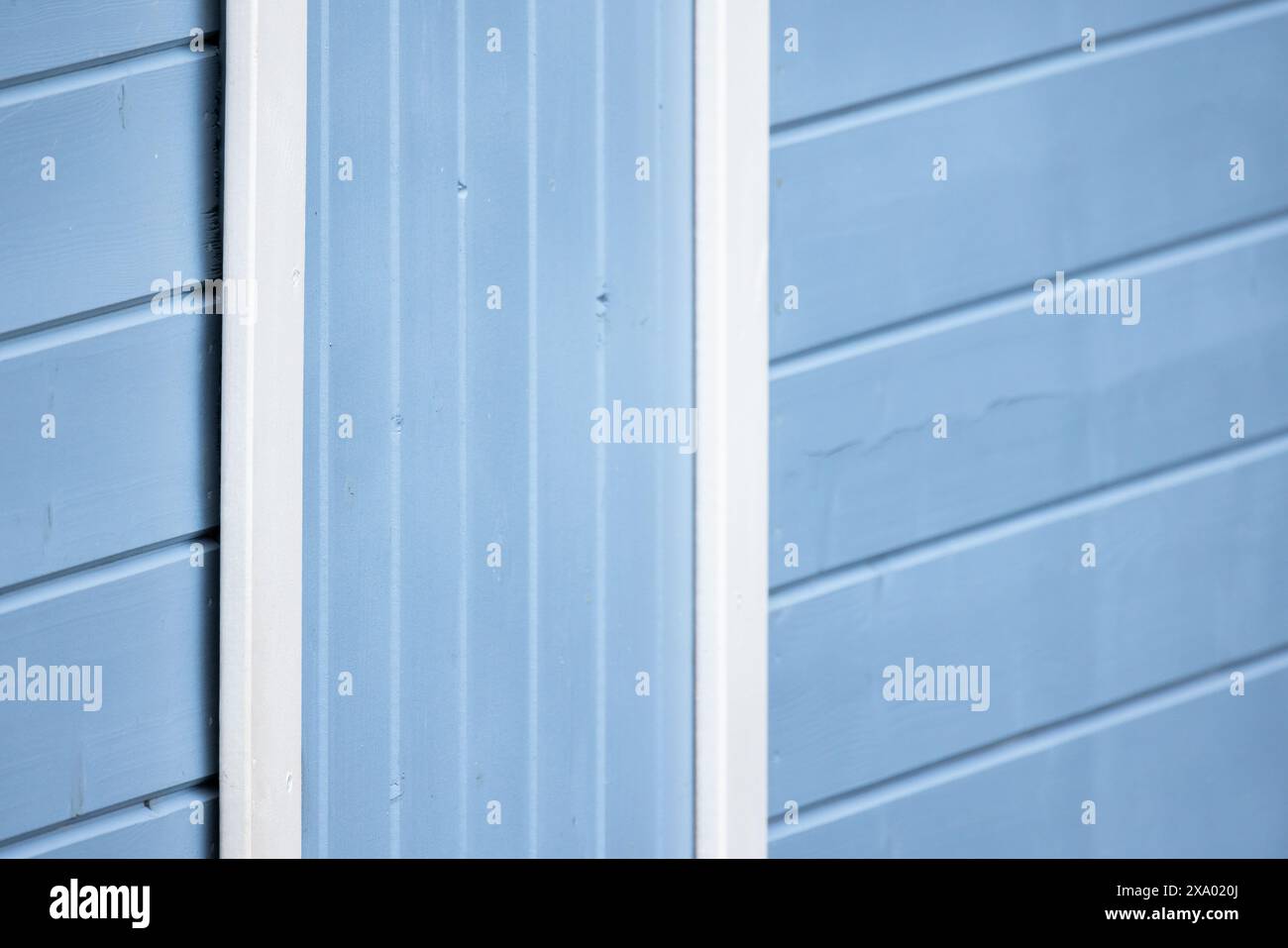 Blaue Holzwand mit weißem Türrahmen, abstraktes Hintergrundfoto mit selektivem Weichfokus Stockfoto