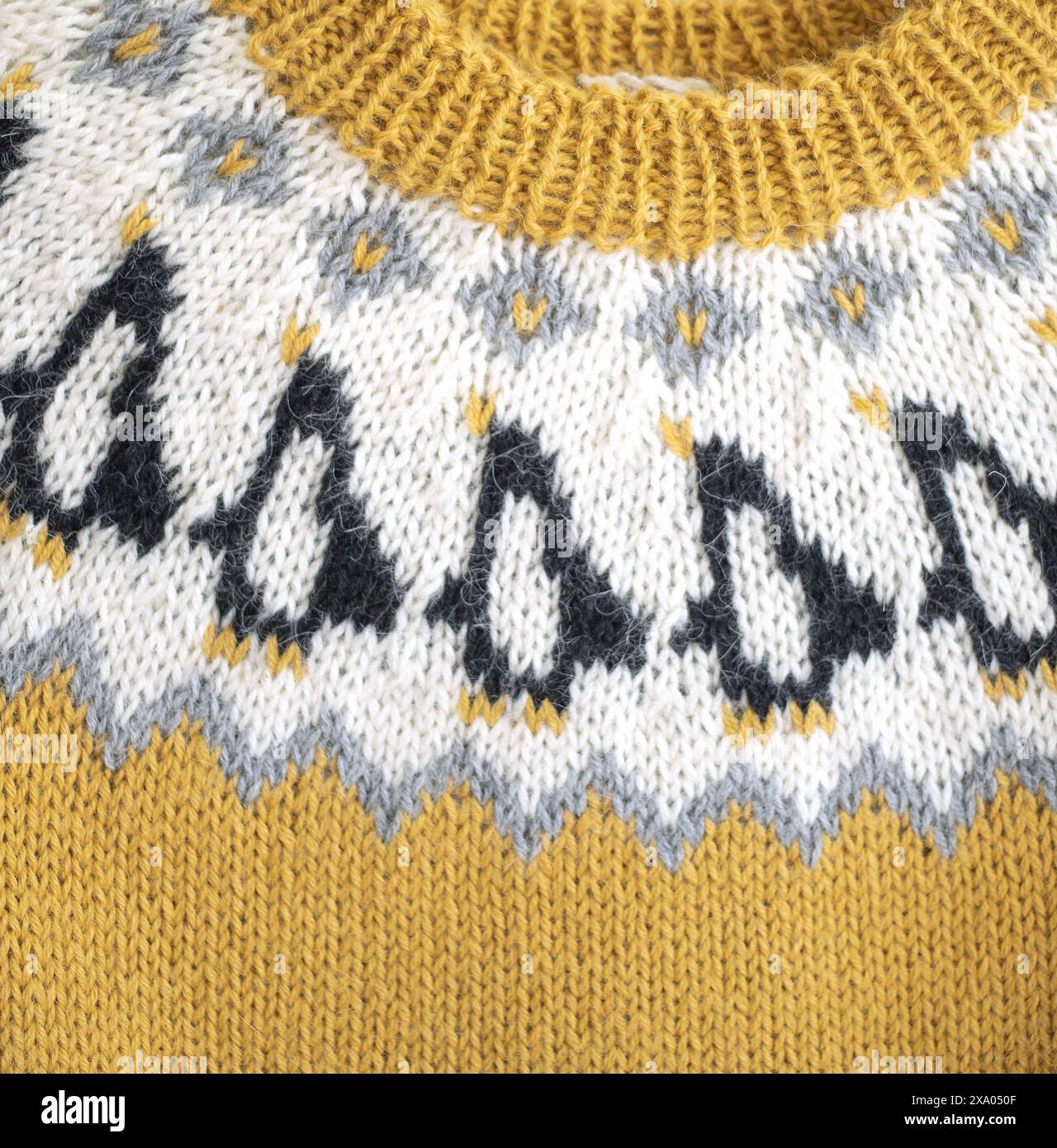 Nahaufnahme eines gelb-weißen, schwarzen, isländischen Strickpullovers für Kinder mit Pinguin-Muster und einer Passe und einem gerippten Nackenbund Stockfoto