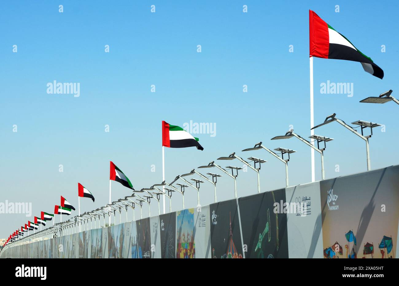 Abu Dhabi, VAE, 11. januar. 2024.- Blick auf eine Dubai Autobahn mit vielen Autos und Flaggen an der Seite. Hghway und Nationalflaggen der vereinigten staaten Stockfoto