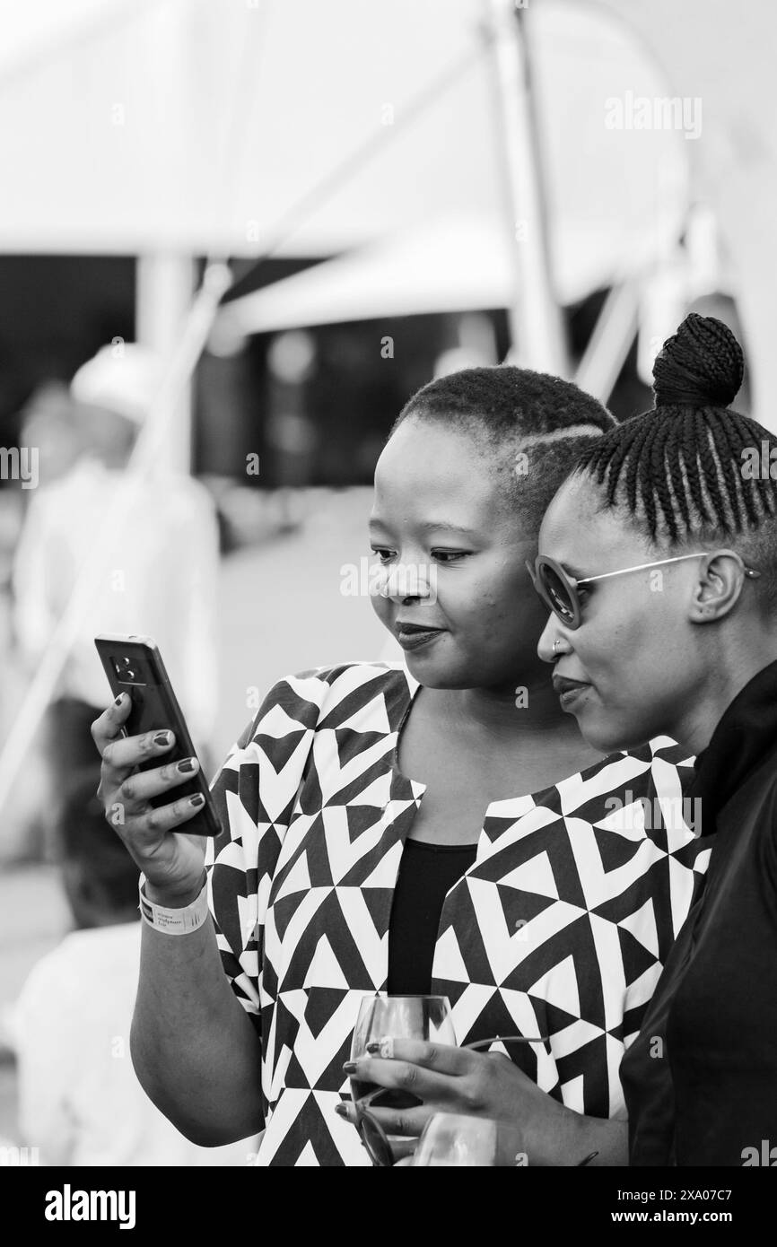 Eine Graustufe von zwei Frauen, die ein Smartphone in Graustufen betrachten Stockfoto