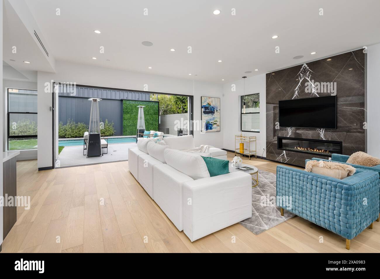Modernes Wohnzimmer mit geräumigen Glasschiebetüren und einem eleganten Flachbildfernseher Stockfoto