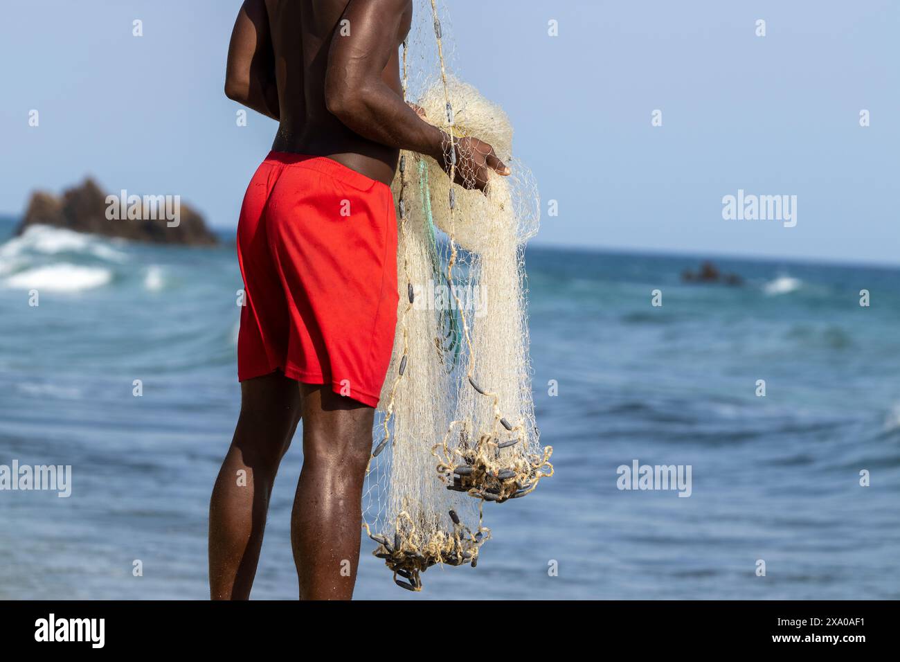 Ein Mann, der ein Fischernetz mit einem erfolgreichen Fang einzieht Stockfoto