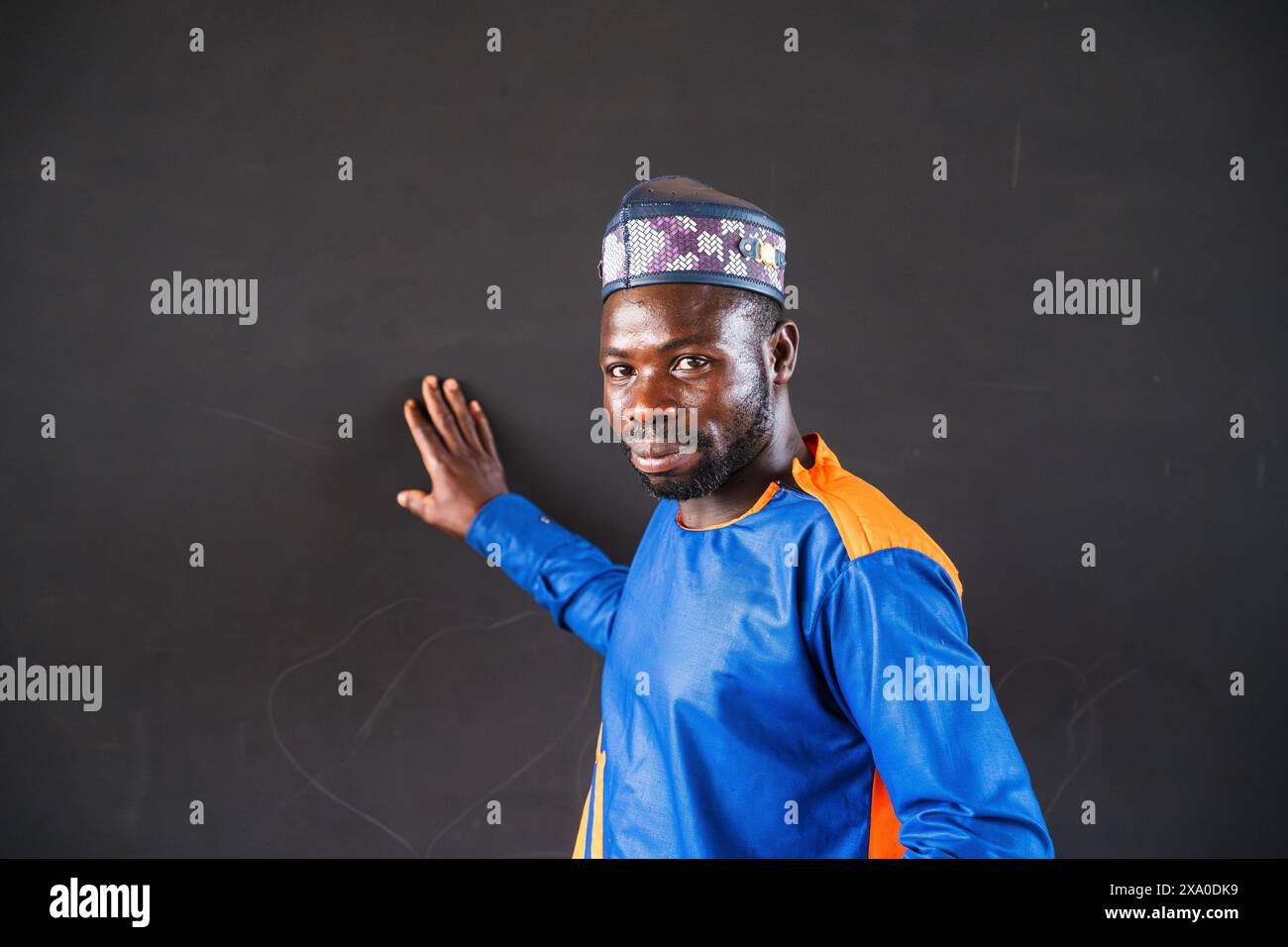 Ein Lehrer in afrikanischem Gewand gegen eine Tafel zur Eröffnung einer Grundschule mit einer deutschen Organisation Stockfoto