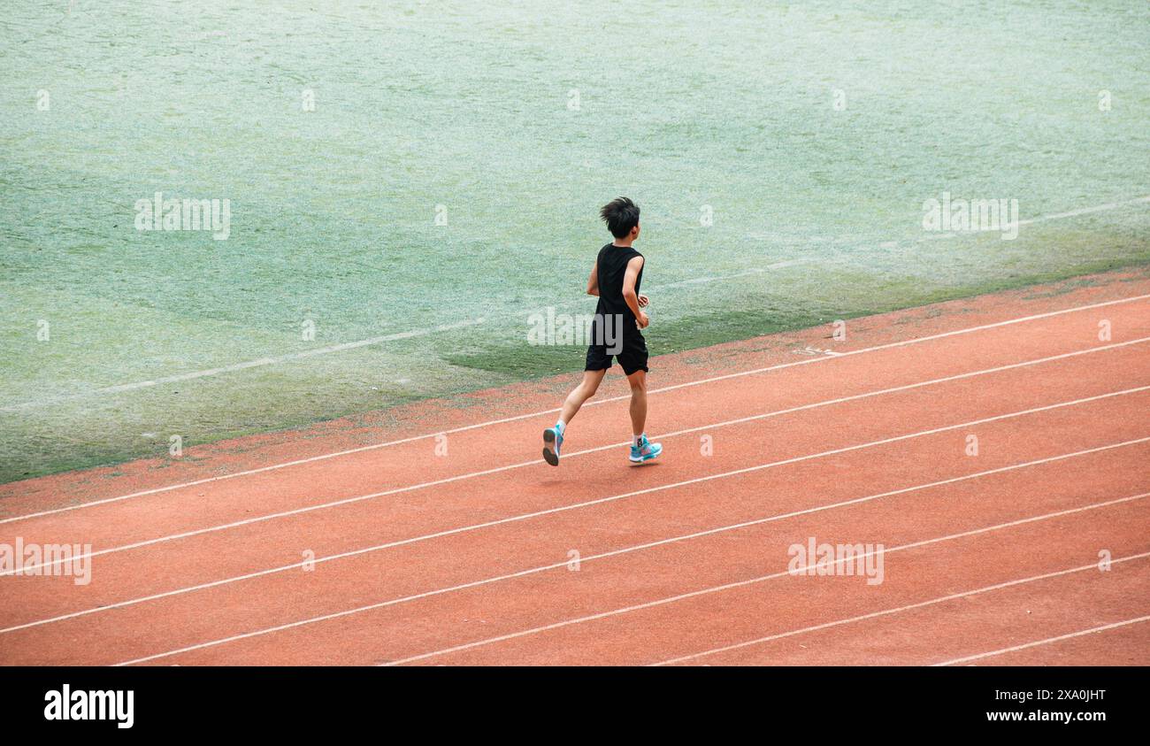 Ein junger Student, der Langstreckenrennen auf einer roten Universitätsstrecke in Wuhan macht. Stockfoto