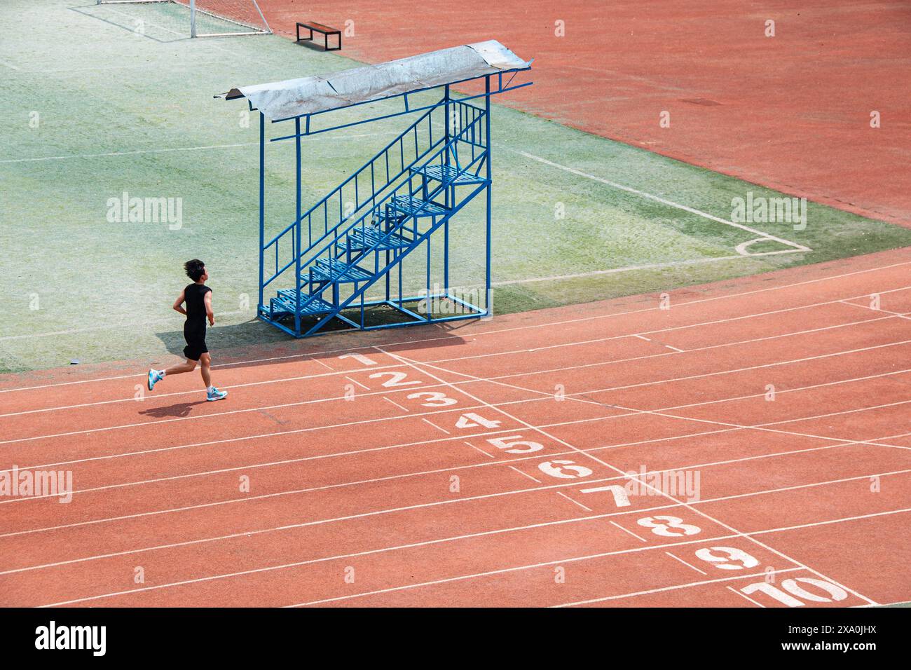 Ein junger Student, der Langstreckenrennen auf einer roten Universitätsstrecke in Wuhan macht. Stockfoto