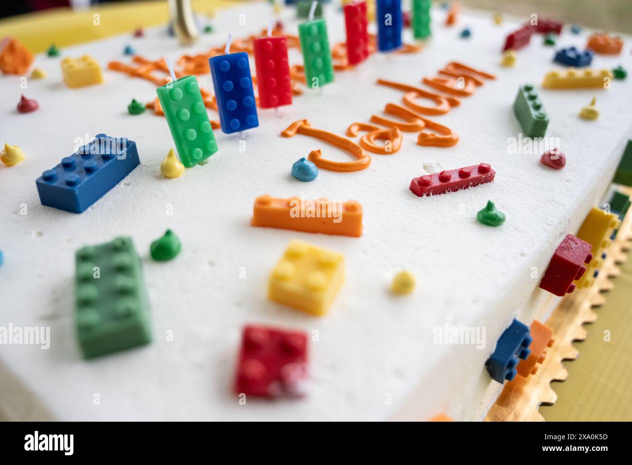 Die Geburtstagskuche hat weiße Zuckerguss und ist mit bunten Bausteinen als Kerzen dekoriert. Stockfoto