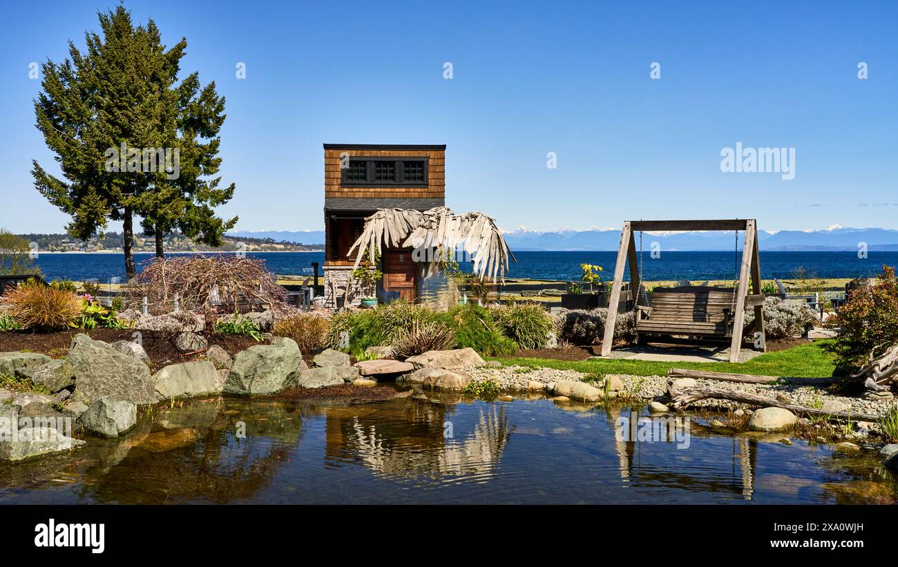 Ein Foto von einem wunderschönen Garten in einem beliebten Resort und Spa mit einem Holzadler aus Treibholz, der sich im Gartenpool spiegelt. Stockfoto