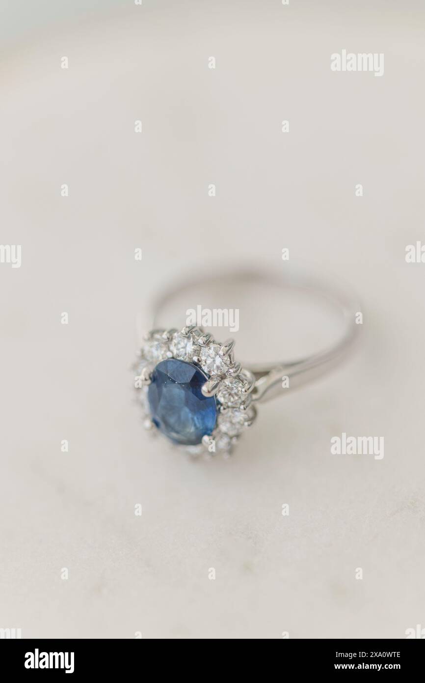 Ein ovaler Saphir und ein runder Diamant-Verlobungsring auf Marmortisch Stockfoto