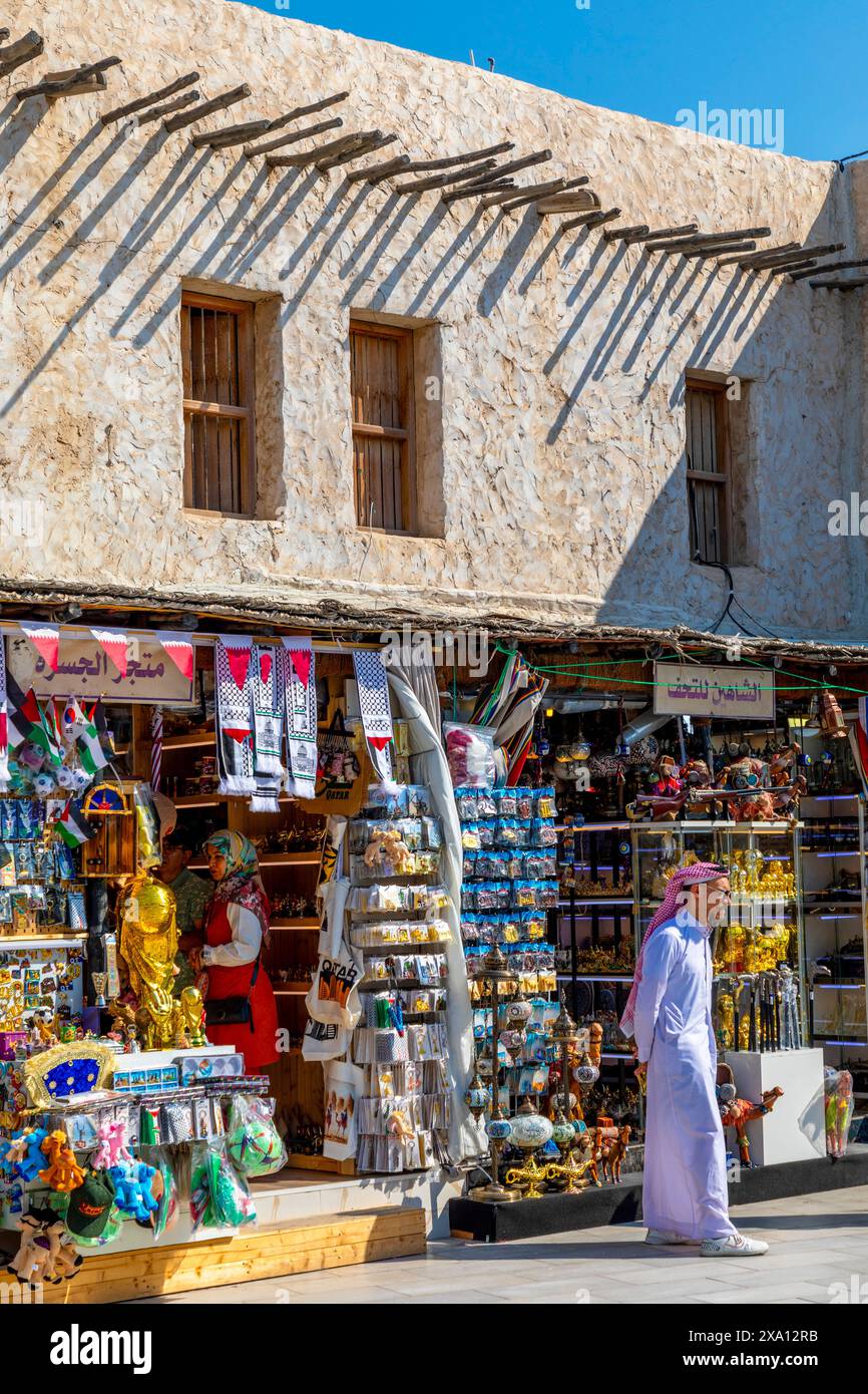 Händler in traditioneller Kleidung im Souq Waqif mit der Fanar-Moschee im Hintergrund, Doha, Katar, Westasien Stockfoto