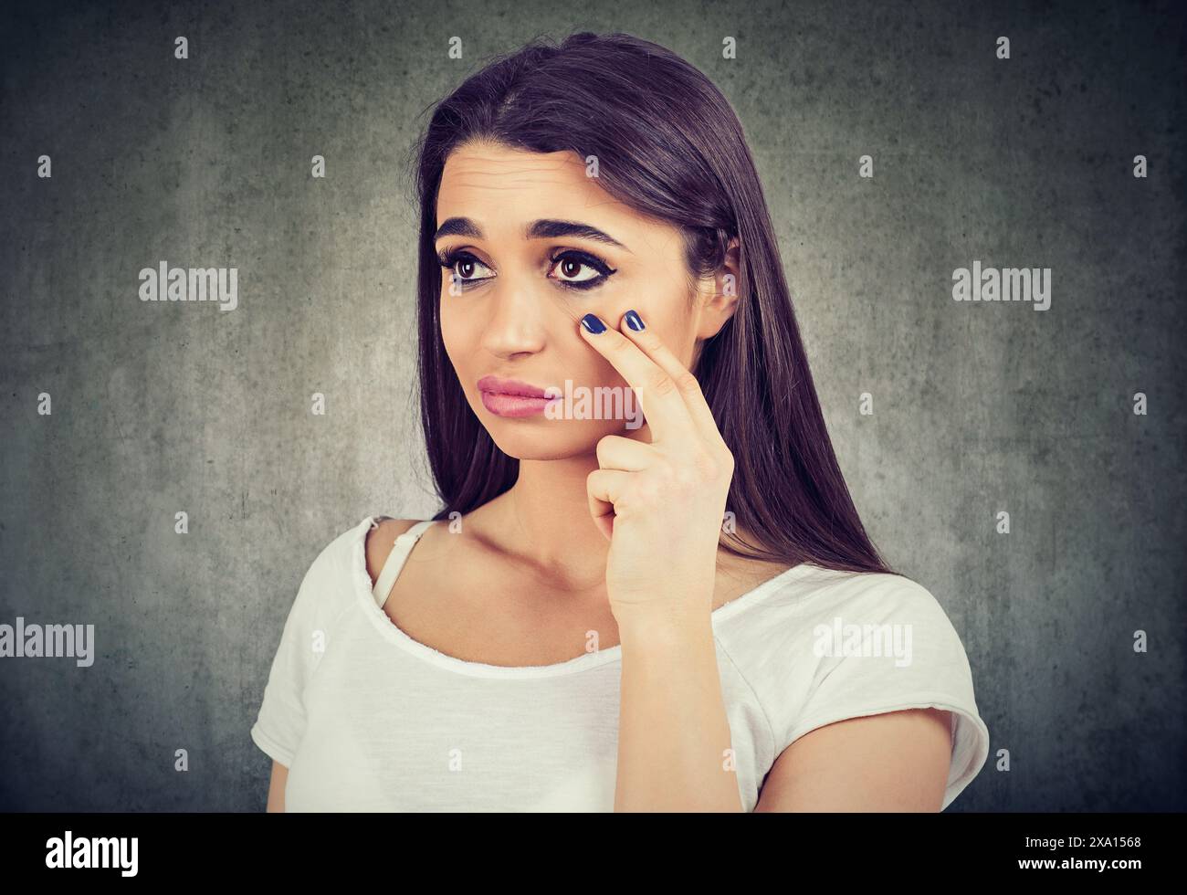 Frau nach unten ziehen, Augenlid ihr Auge in Morrow Kontrolle unwohl fühlt, hat schwarze Kreise Stockfoto