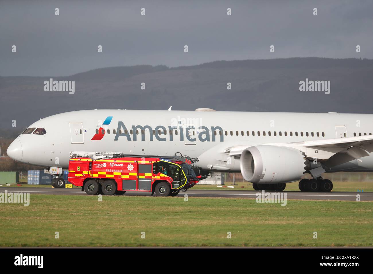 Das Flugzeug der American Airlines auf der Landebahn neben einem Rettungsfahrzeug in Glasgow, Großbritannien. Stockfoto