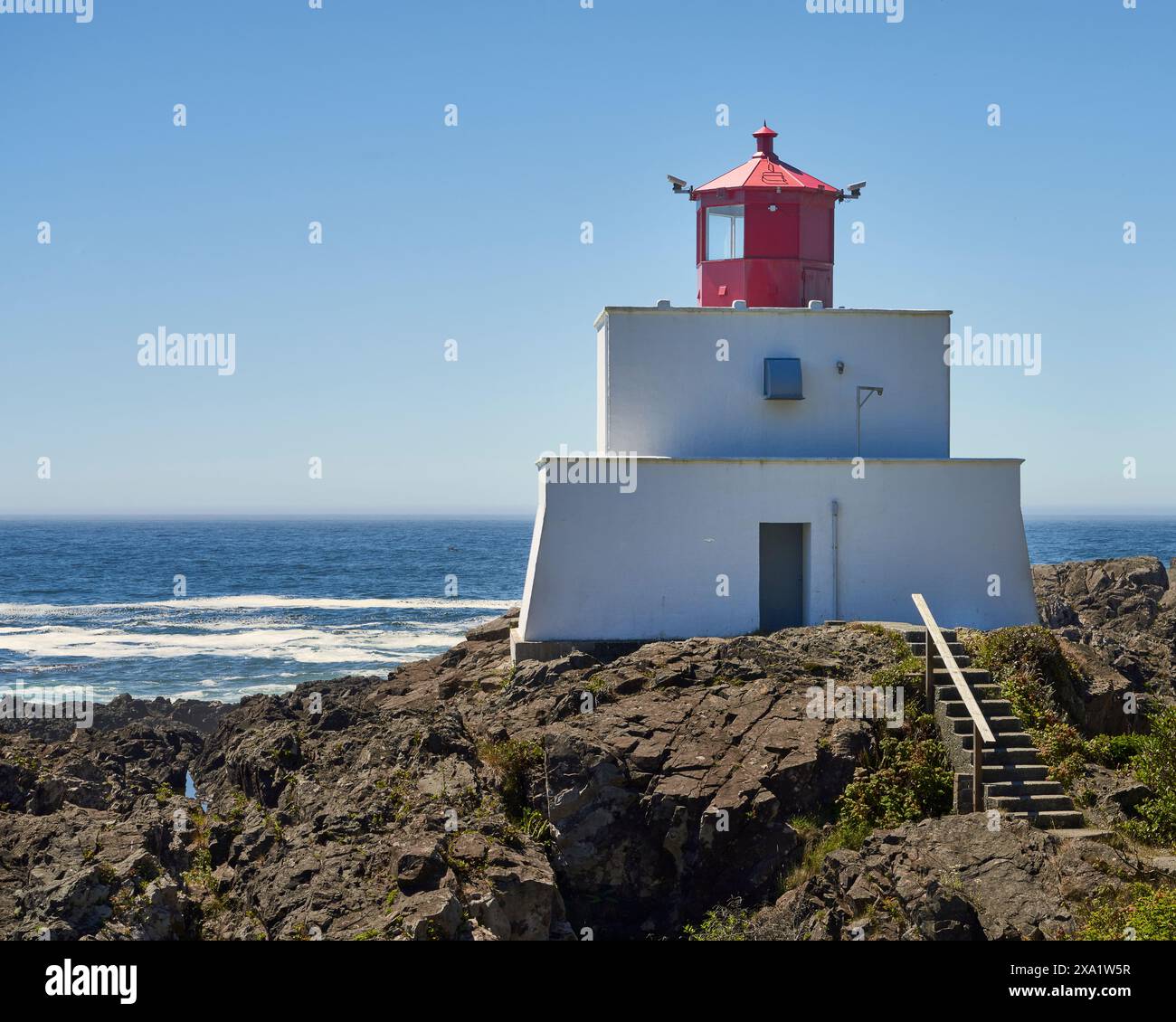 Der ungewöhnlich gestaltete historische Amphitrite Point Lighthouse in weiß und rot liegt hoch über dem tiefblauen Ozean. Stockfoto