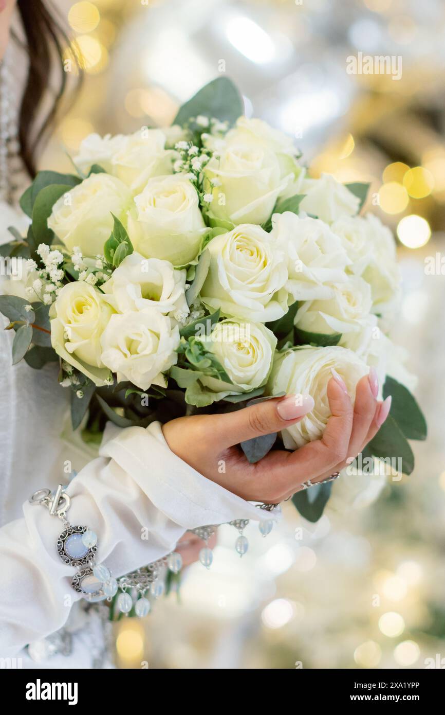 Die Frau, die einen Hochzeitsstrauß mit goldenem Hintergrund hält Stockfoto