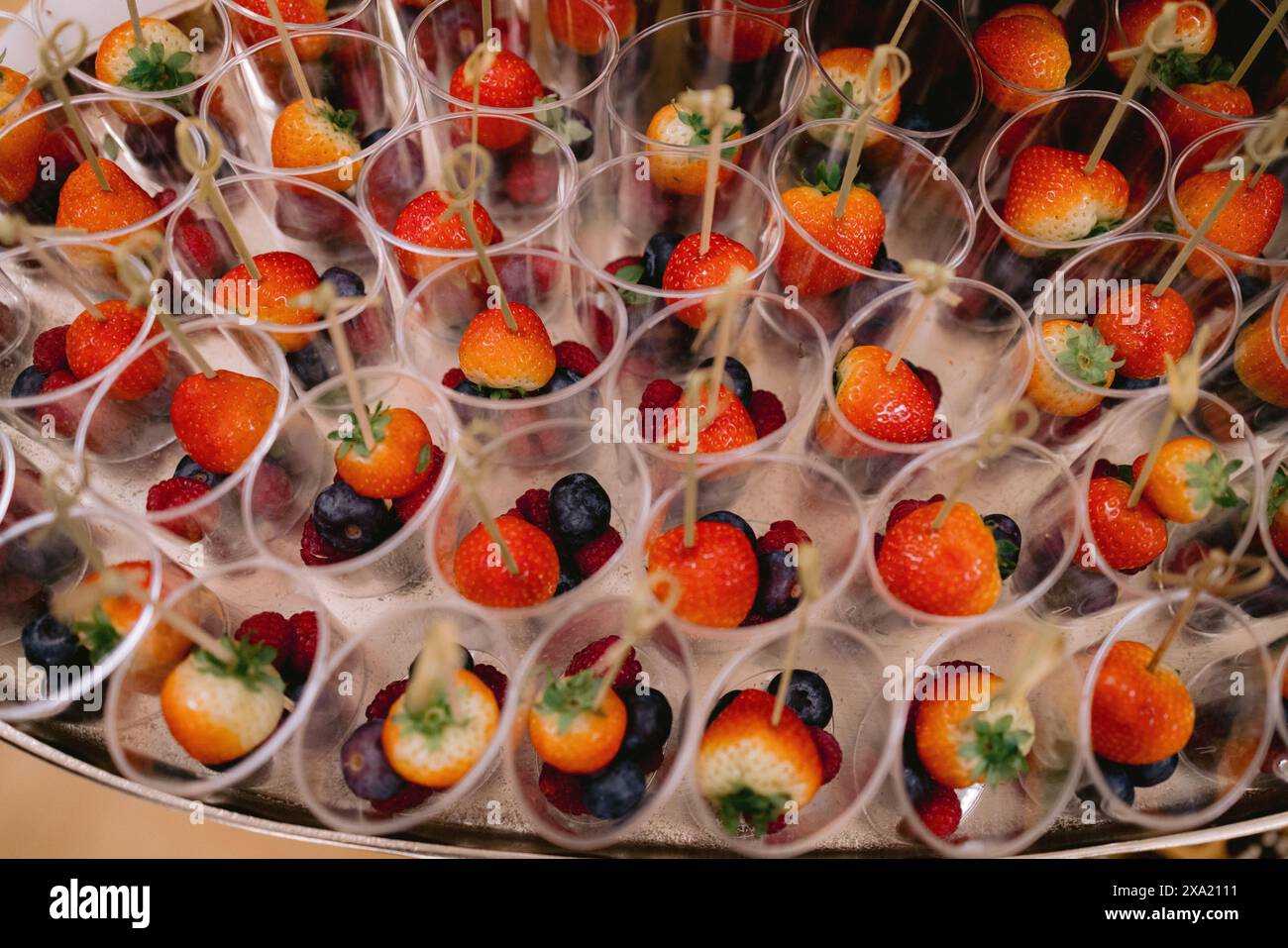 Verschiedene Tassen gefüllt mit Erdbeeren, Kirschen, Heidelbeeren und verschiedenen Beeren Stockfoto