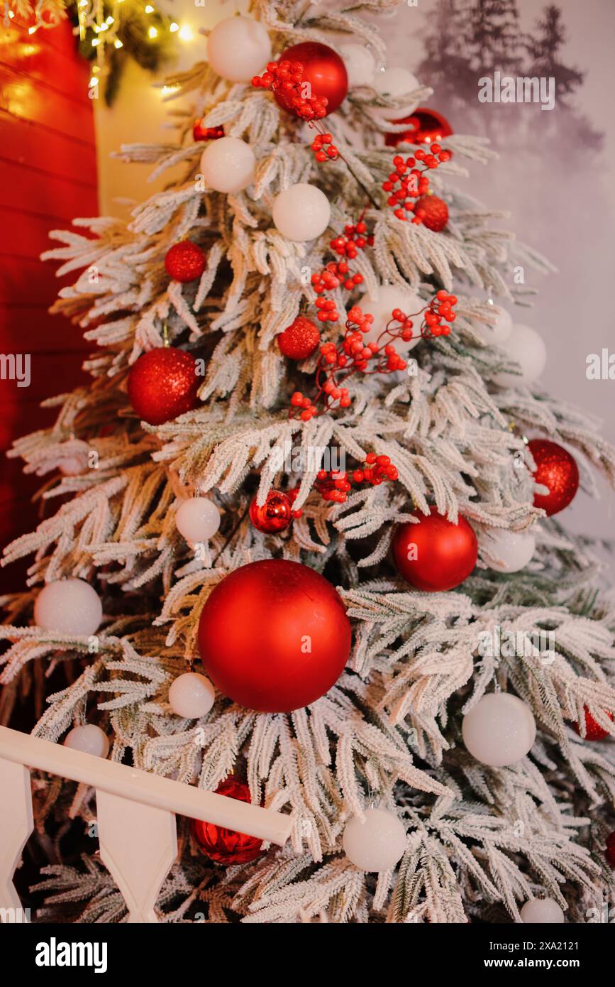 Festlicher Weihnachtsbaum mit roten und weißen Ornamenten in einem gemütlichen Raum Stockfoto
