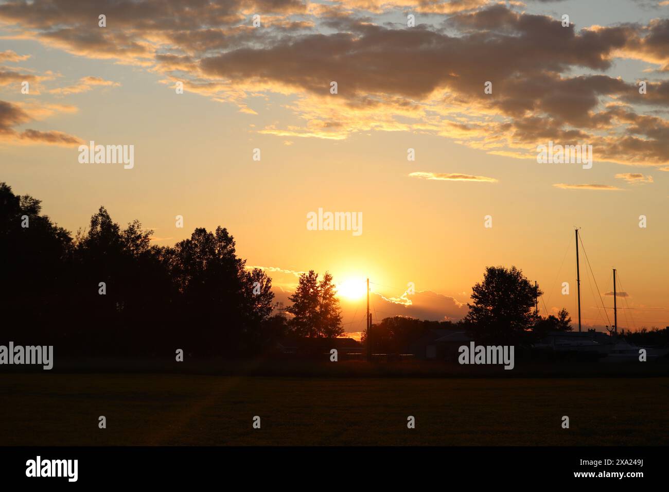 Die Sonne untergeht hinter zahlreichen hellen Wolken Stockfoto