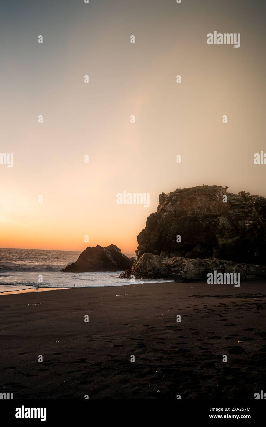 Ein felsiger Strand bei Sonnenuntergang mit farbenfrohem Himmel Stockfoto