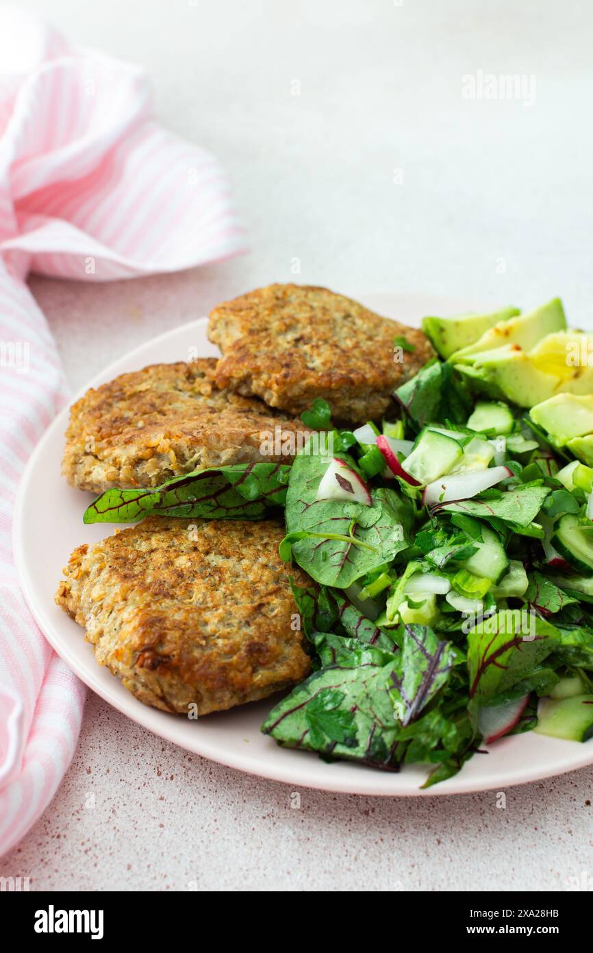 Quinoa-Schnitzel und gemischter Salat mit Avocado und Radieschen, Kiwi und Wasser mit Zitrone, köstliches herzhaftes Frühstück, veganer Lunch-Teller Stockfoto