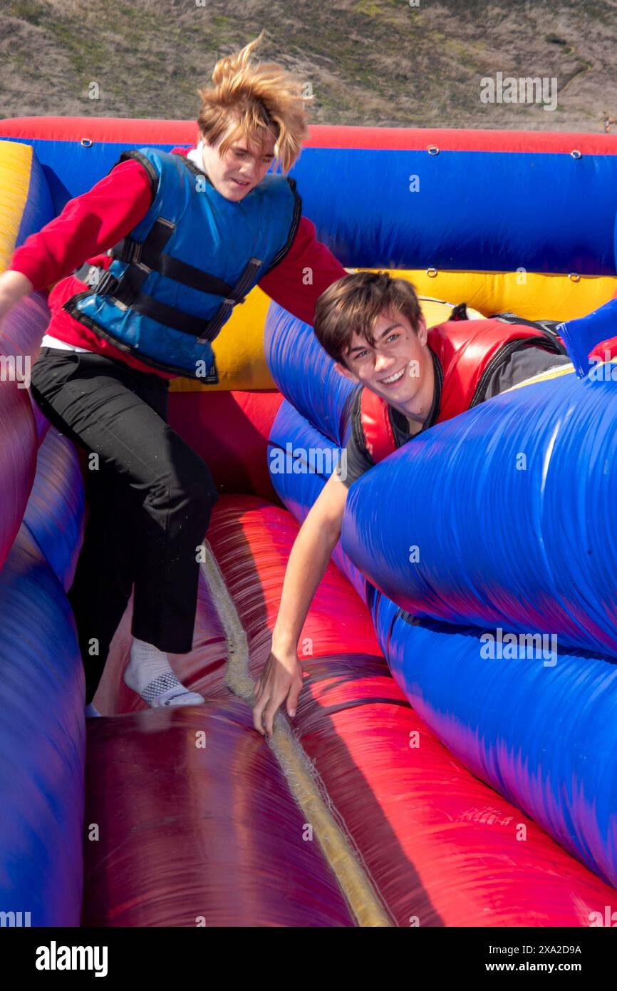 Schüler der High School im Süden Kaliforniens genießen eine Bungee-Run-Folie bei einem Semester-End-fest. Der Bungee Run ist ein kompetitives aufblasbares Design Stockfoto