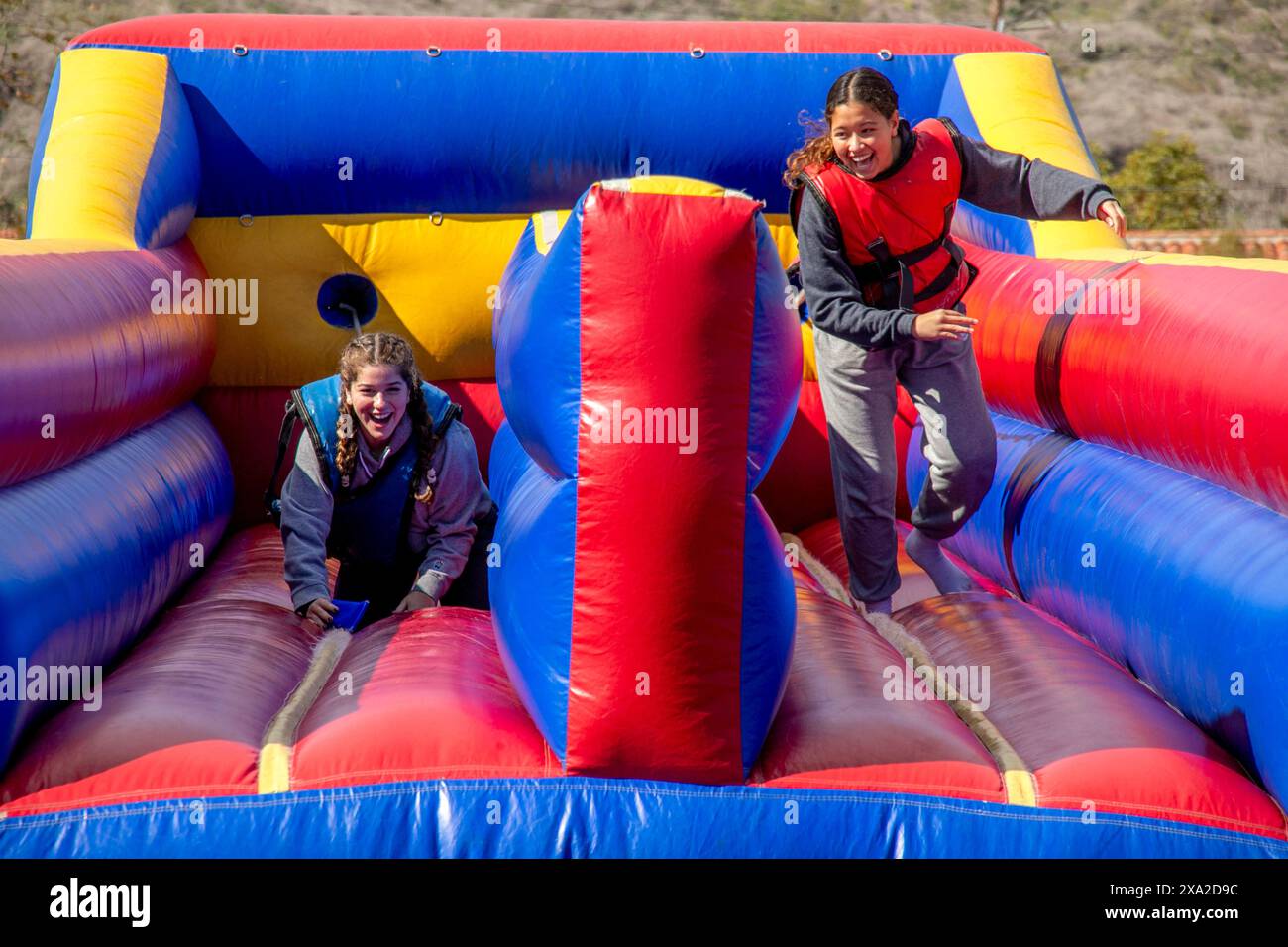 Schüler der High School im Süden Kaliforniens genießen eine Bungee-Run-Folie bei einem Semester-End-fest. Der Bungee Run ist ein kompetitives aufblasbares Design Stockfoto