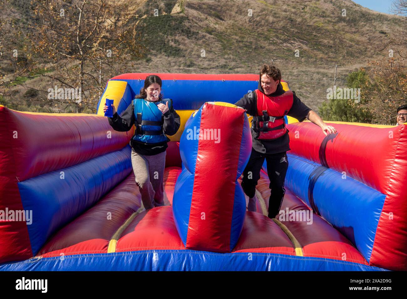 Schüler der High School im Süden Kaliforniens genießen eine Bungee-Run-Folie bei einem Semester-End-fest. Der Bungee Run ist ein kompetitives aufblasbares Design Stockfoto