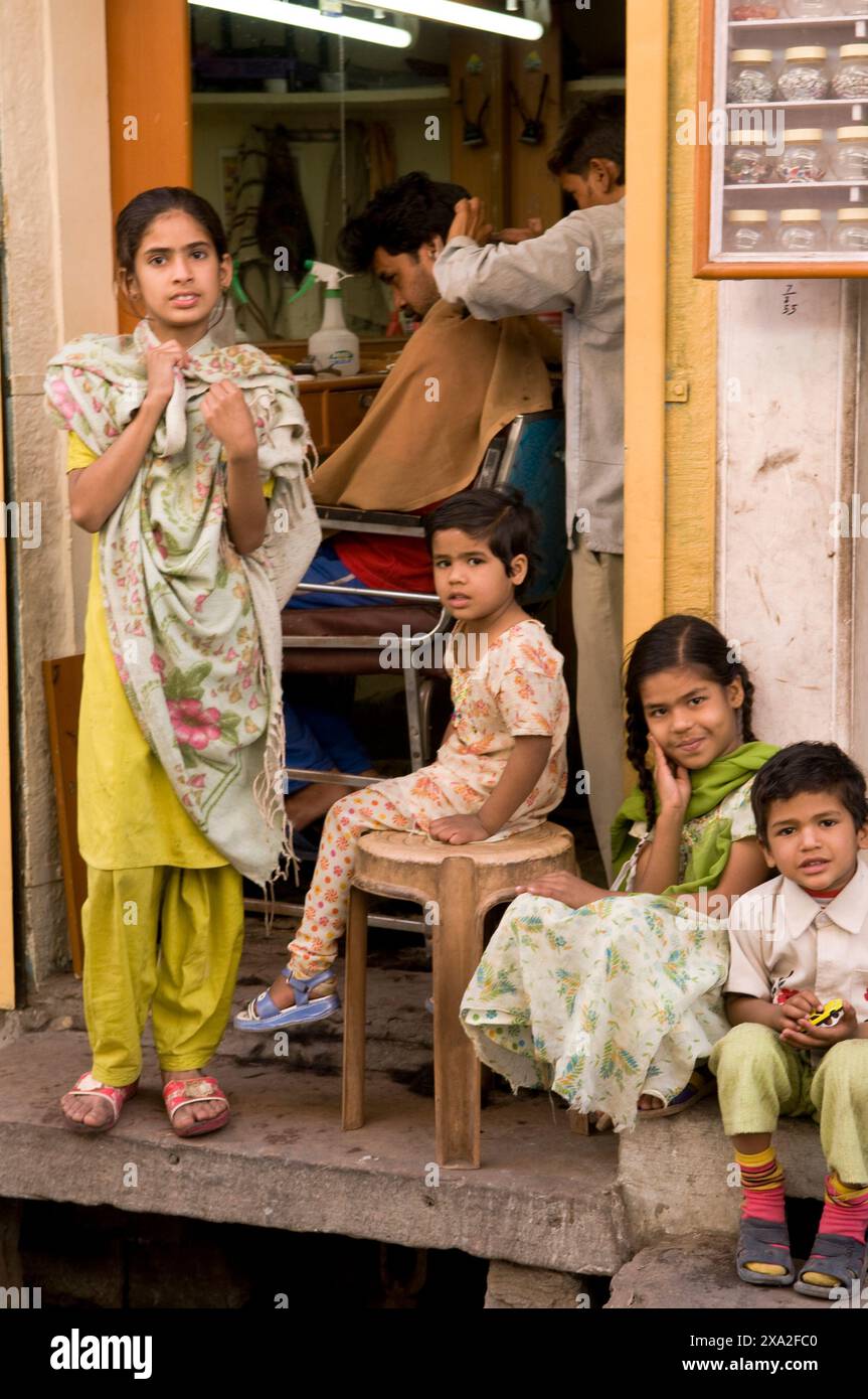 Niedliche Kinder, die vor einem Friseurladen in Jodhpur, Rajasthan, Indien sitzen. Stockfoto