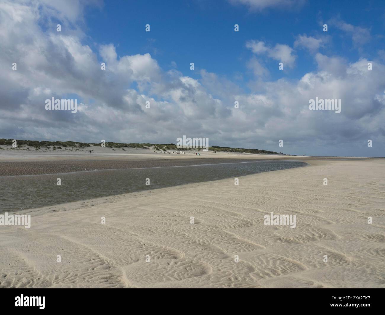 Ein breiter, leerer Strand unter bewölktem Himmel, mit Dünen im Hintergrund, Spiekeroog, Deutschland Stockfoto