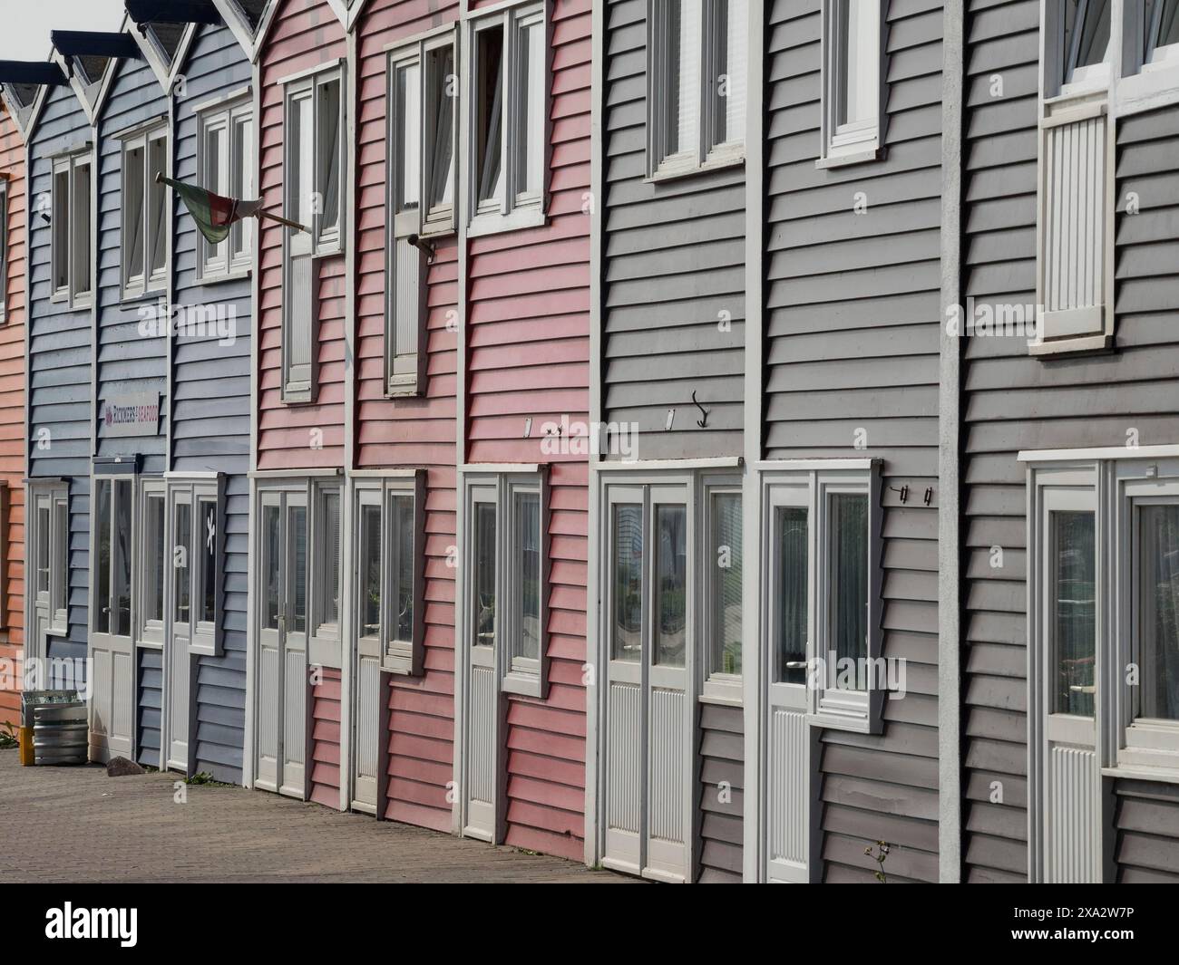 Pastellfarbene Gebäude in Folge, darunter grau, rosa und blau, gemütliche urbane Atmosphäre, Helgoland, Deutschland Stockfoto