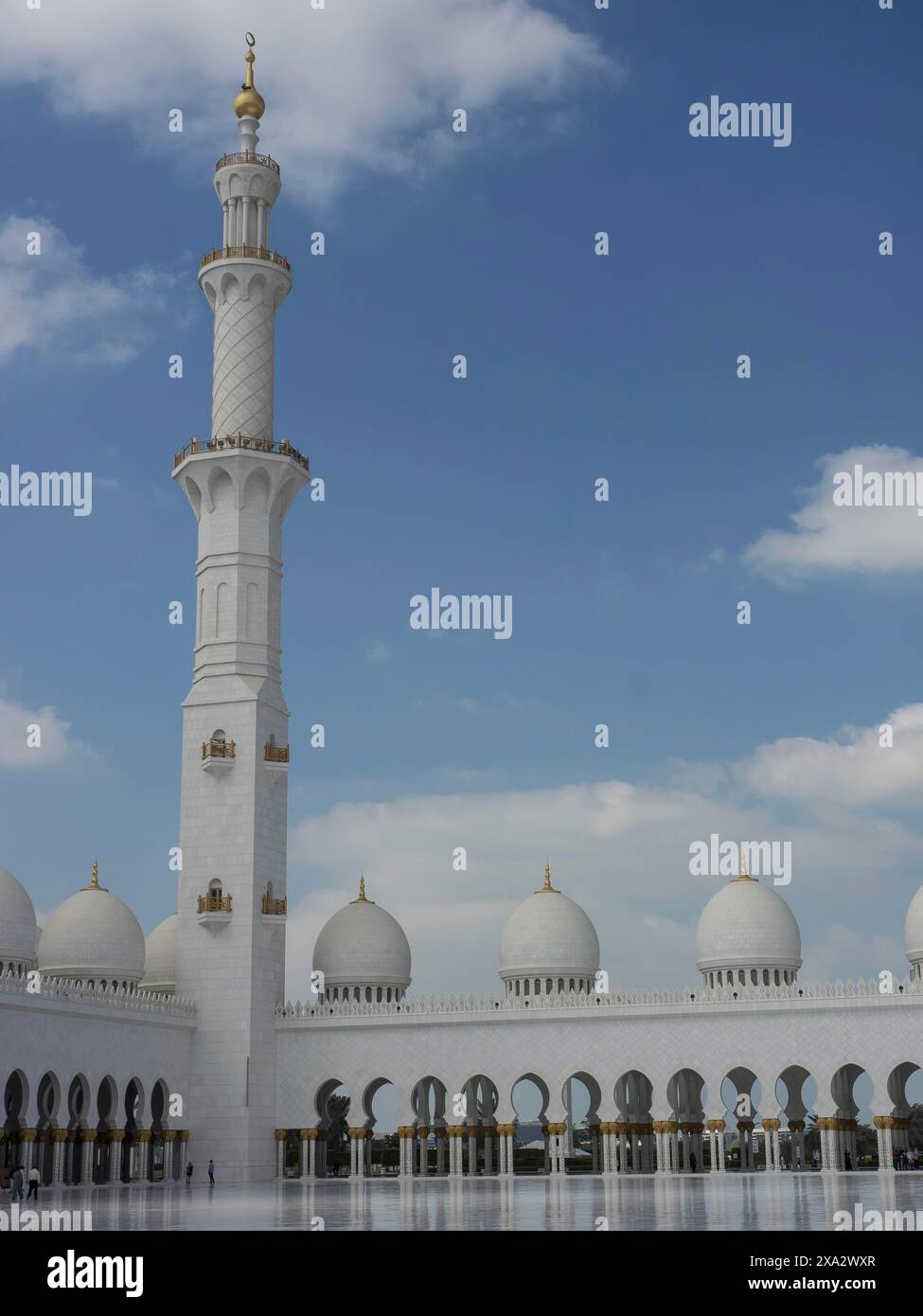 Minarett und weiße Gebäude einer Moschee mit Bögen, dargestellt in islamischer Architektur unter blauem Himmel, Abu Dhabi, Arabische Emirate Stockfoto