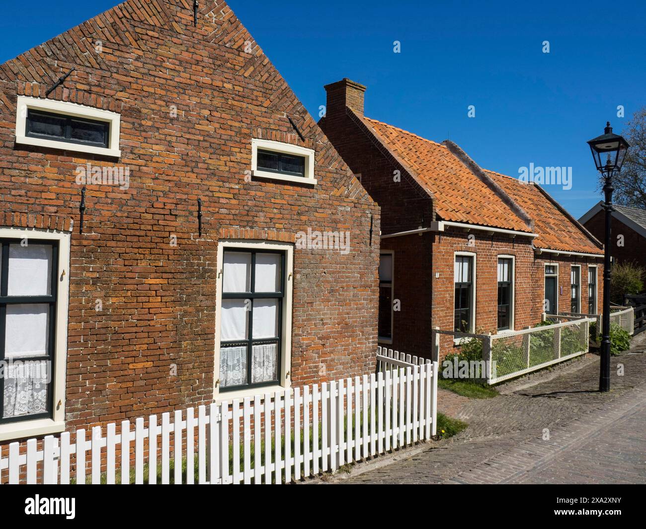 Traditionelle Backsteinhäuser und weiß gestrichene Fensterrahmen unter blauem Himmel, Enkhuizen, Nirderlande Stockfoto