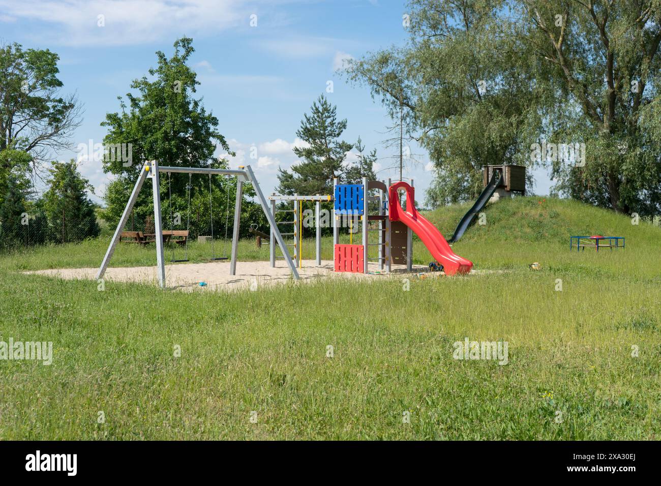 Verlassener Spielplatz mit Rutsche, Klettergerüst und Schaukel am Mittag Stockfoto