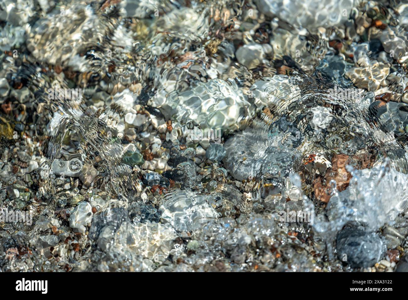 Strand mit bunten kleinen runden Steinen an einem sonnigen Tag Stockfoto