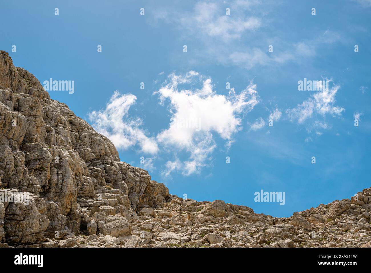 Felsiger Hügel mit Wolken im Hintergrund an einem sonnigen Tag Stockfoto