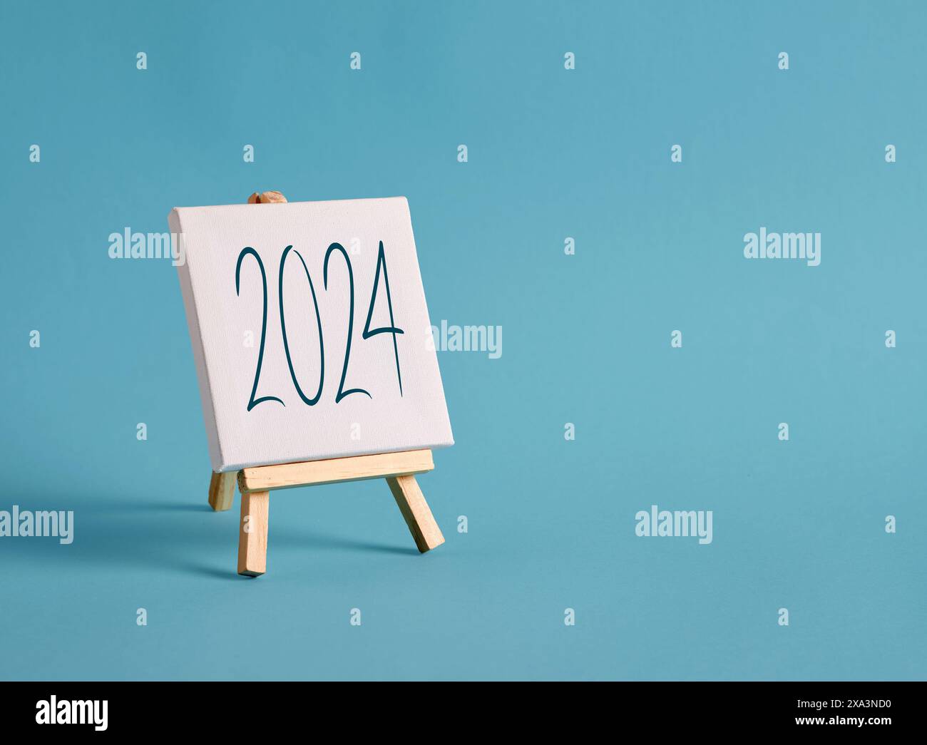Eine Leinwand mit dem Jahr 2024 auf einer Staffelei mit blauem Hintergrund. 2024 Geschäftspläne, Zielvorgaben und Strategien. Stockfoto